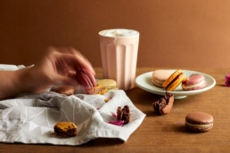 A hand taking macaron from a plate