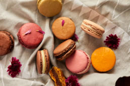 Assortment of colorful macarons with fresh flowers on linen cloth