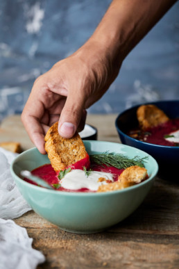 Bowl of Beetroot soup with coconut milk and sour cream, garnished with parsley, served with baked bread