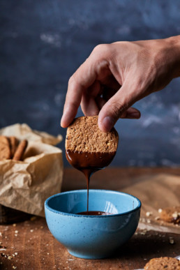 Dipping walnut cookie in melted chocolate