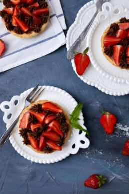 Mini tart with strawberry jam, served with fresh strawberries and chocolate ganache