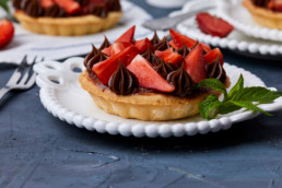 Mini tart with strawberry jam, served with strawberries and chocolate ganache