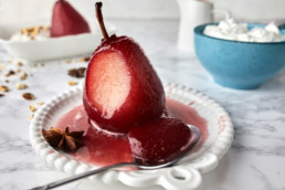 Pears poached in red wine with spices served with cream, topped with wine sauce