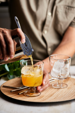 Pouring a mix of fresh juices through a metal sieve into a glass