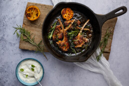 Baked lamb chops with fresh rosemary in a skillet and goat cheese with basil