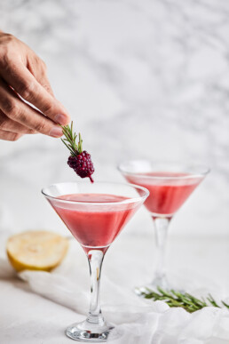 Garnishing mocktail with fresh rosemarry twig and blackberry