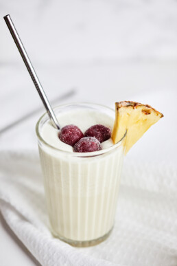 Pineapple and coconut mocktail garnished with pineapple and frozen cherries