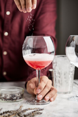 Sprinkling a mixture of hibiscus tea, lavender and sugar onto the mocktail